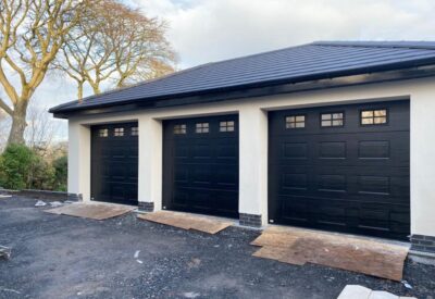 Three black garage doors with newly rendered garage